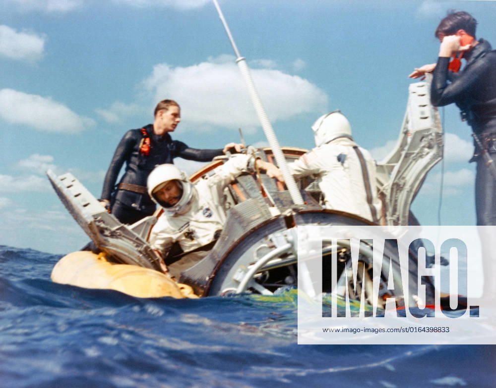 S65-61886 (16 Dec. 1965) --- A water level view of Navy divers assisting Gemini-6 crew members Stafford and Schirra to open hatches after landing in the Atlantic.