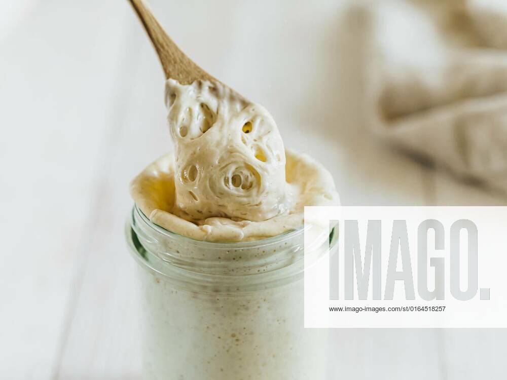 Ready for making bread sourdough starter, Ready for making bread wheat sourdough starter dripping from wooden spoon. Glass jar with sourdough starter 100 percent hydration on white wooden background. Copy space. Homemade breadmaking concept, Ready for making bread wheat sourdough starter dripping from wooden spoon. Glass jar with sourdough starter 100 percent hydration on white wooden background. Copy space. Homemade breadmaking concept, 17.05.2020,