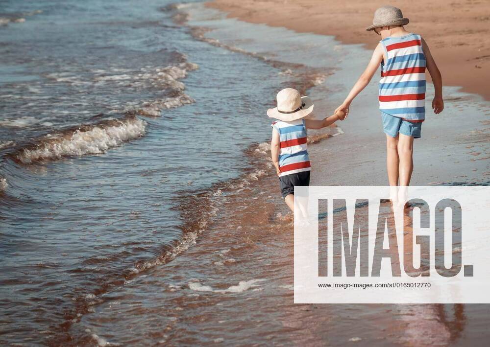 Two brothers are walking on the beach, Two brothers barefoot are walking on the beach in water. Boys are on vacation in summer at the sea, Two brothers barefoot are walking on the beach in water. Boys are on vacation in summer at the sea model released, Symbolfoto , 01.11.2020,