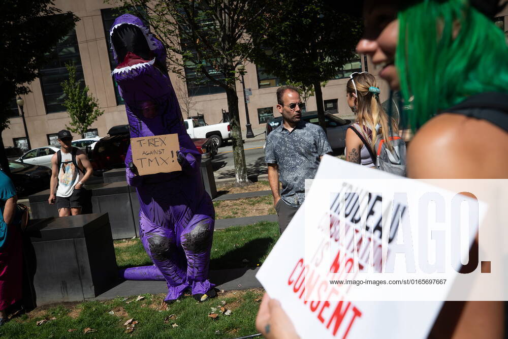 A person wearing a dinosaur costume holds a sign during a protest against fracking led by Wet suwet en hereditary chiefs in Vancouver, on Monday, August 15, 2022. VANCOUVER CANADA - ZUMAc35_ 20220815_zaf_c35_041