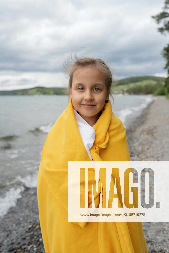 IMAGO Creative: Ende des Sommers Side view of thoughtful girl standing by the sea wrapped in a yellow blanket on a cold day looking at camera, Model released LiliyaSolopova_MayaVaravaraAndVenera_00037.jpg