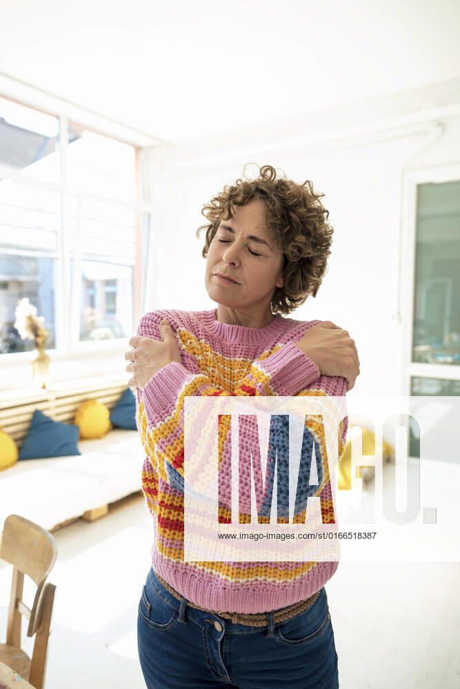 Woman with eyes closed hugging self at home model released, Symbolfoto property released, JOSEF11629