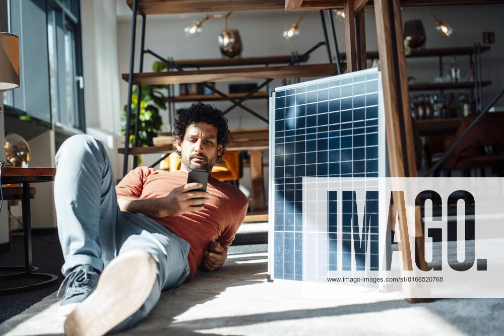 IMAGO Creative: 2022 Favoriten IMAGO Creative: Klimawandel - Klimabewusst Businessman using smart phone by solar panel at workplace model released, Symbolfoto property released, JOSEF11800