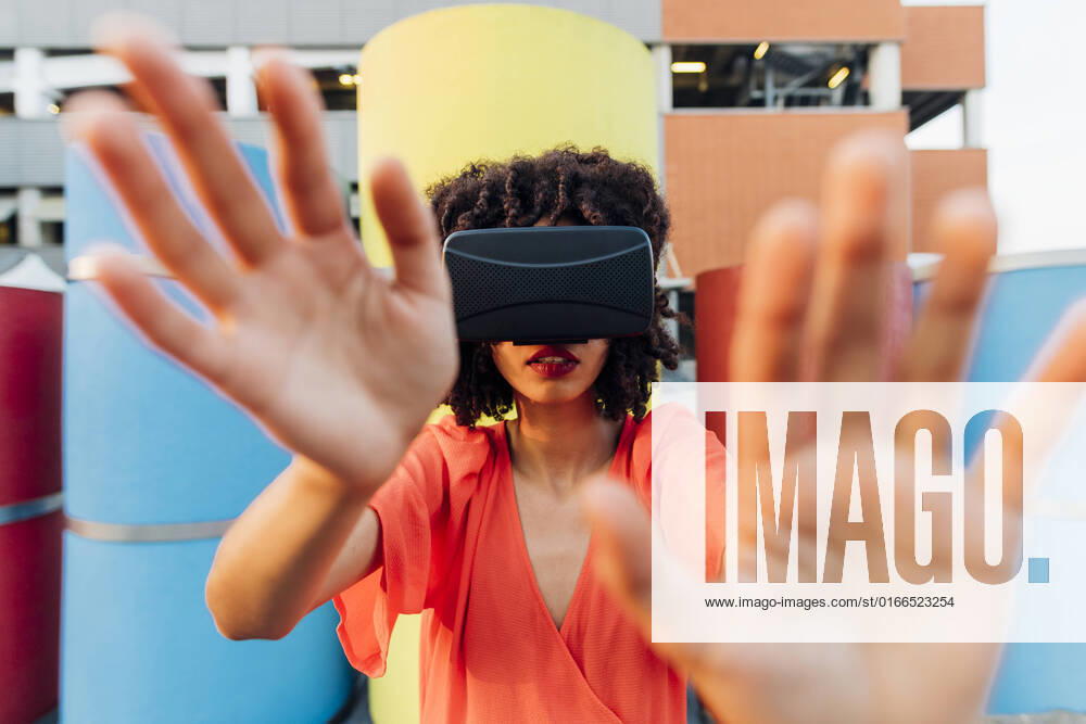 IMAGO Creative: 2022 Favoriten IMAGO Creative: Internationaler Tag der Architektur am 3. Oktober. Thema: Architektur zum Wohlfühlen Woman wearing virtual reality simulator gesturing in front of multi colored pipe model released, Symbolfoto, MEUF07019