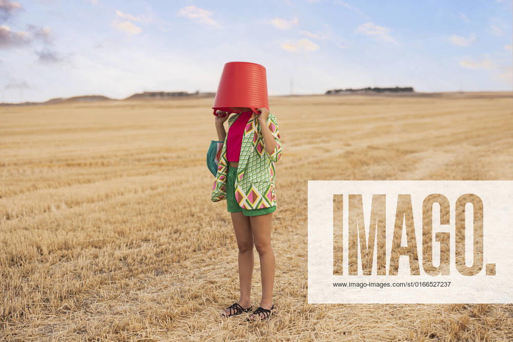 Woman covering face with bucket at field model released, Symbolfoto, JCCMF06914