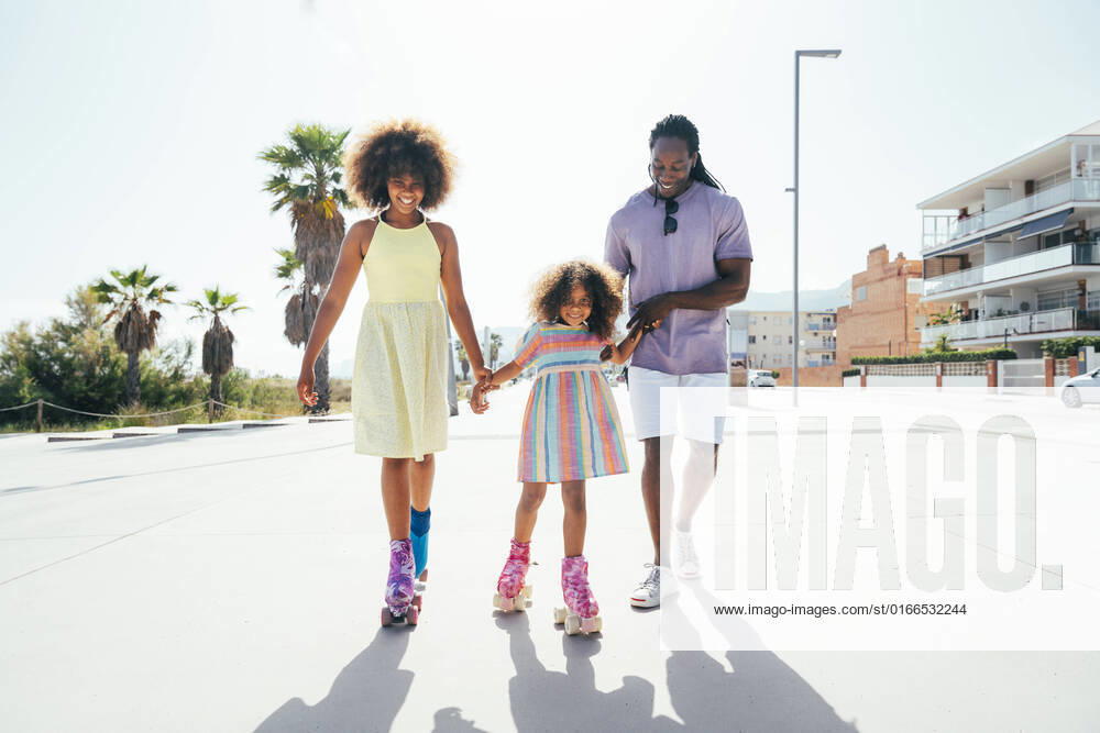 Smiling daughters roller skating with father on sunny day model released, Symbolfoto, OIPF02192