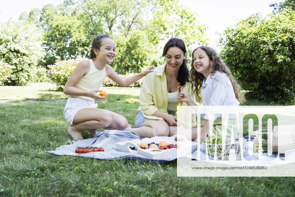 Happy daughters having picnic with mother at park on weekend model released, Symbolfoto, OSF00500