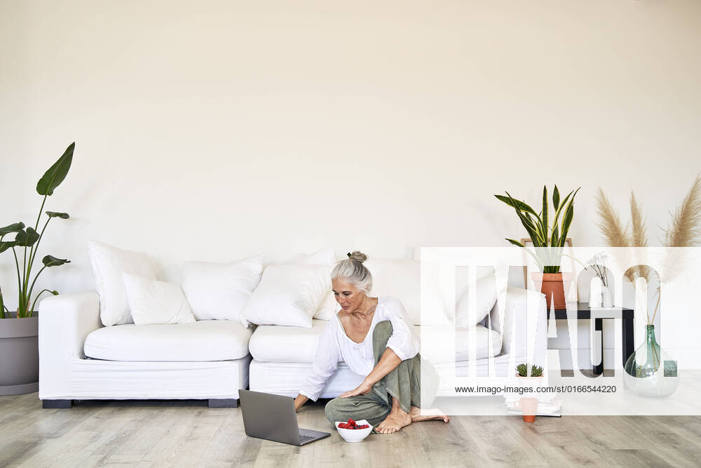 IMAGO Creative: Business, Innovative Technologie-Lösungen Woman using laptop sitting on floor in living room model released, Symbolfoto property released, VEGF05801