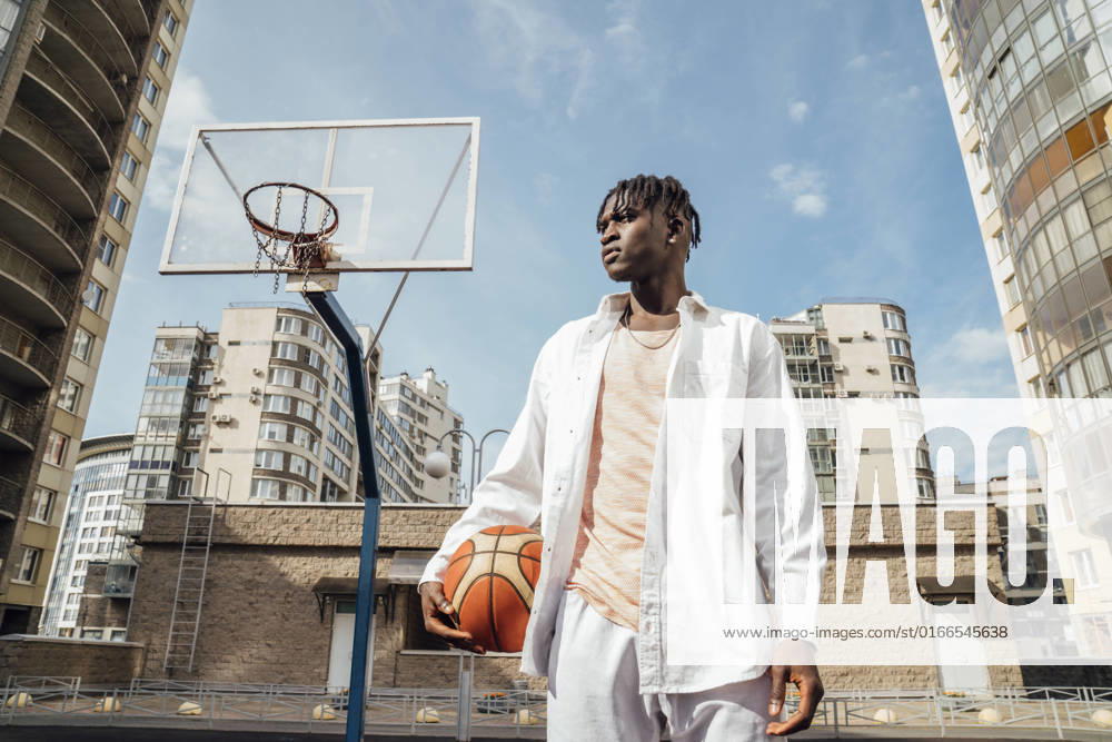 IMAGO Creative, Urban Lifestyle Young man with basketball at sports court on sunny day model released, Symbolfoto, VPIF06862