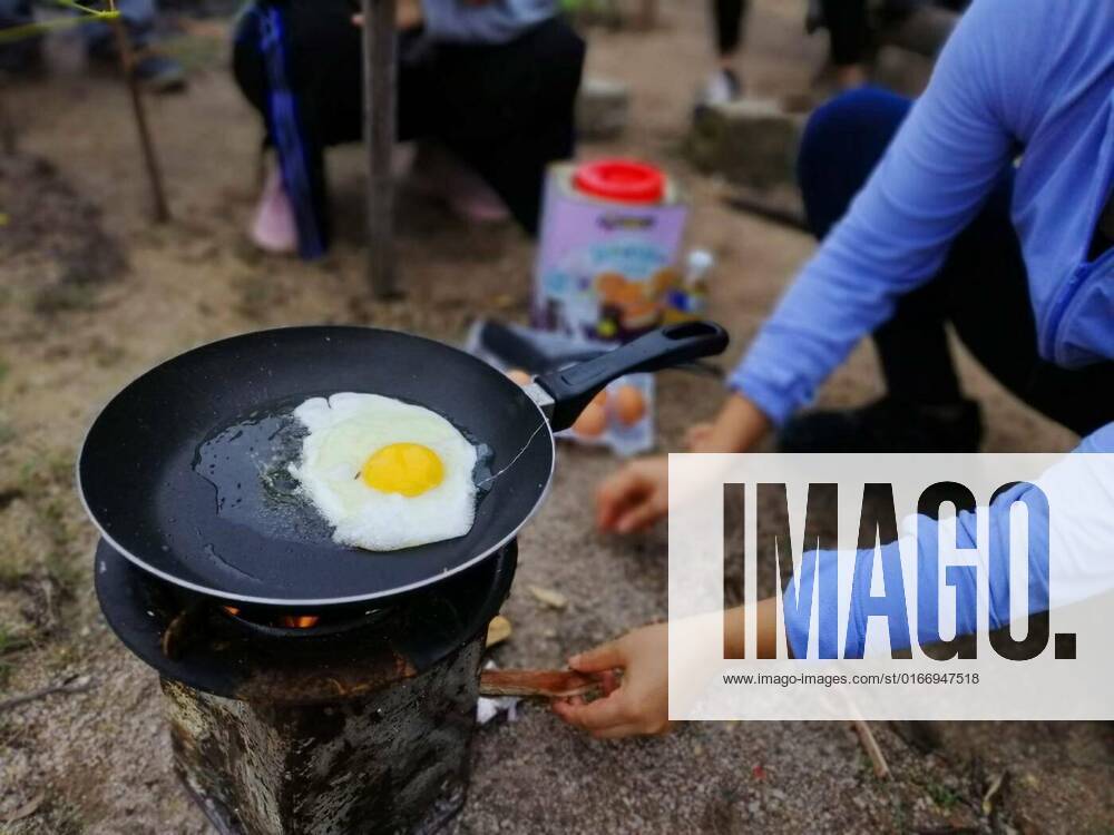 IMAGO Creative: Ende des Sommers Outdoor camp fire and cooking, Cooking breakfast on campfire in cast iron pan with selective focus., 27.05.2021,