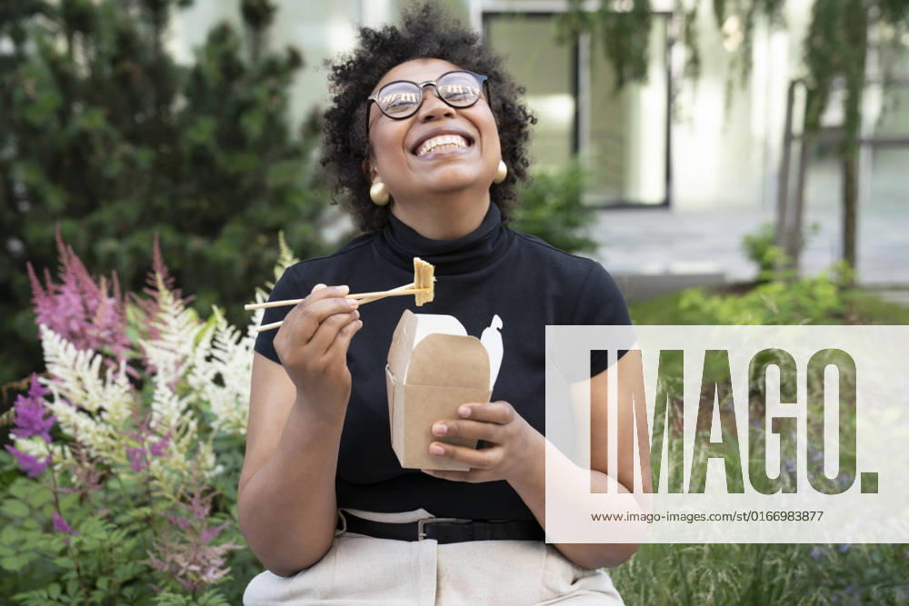Happy young businesswoman with chopsticks and take out food sitting in office park model released, Symbolfoto, VPIF06975