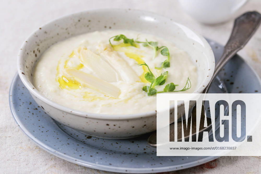 IMAGO Creative: Food, Spargel White asparagus soup Bowl of white asparagus cream soup with pea sprouts and toast, served with jug of milk over gray tablecloth