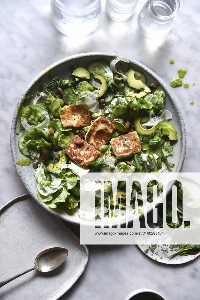 Green Salad with halloumi and dressing in a ceramic bowl.