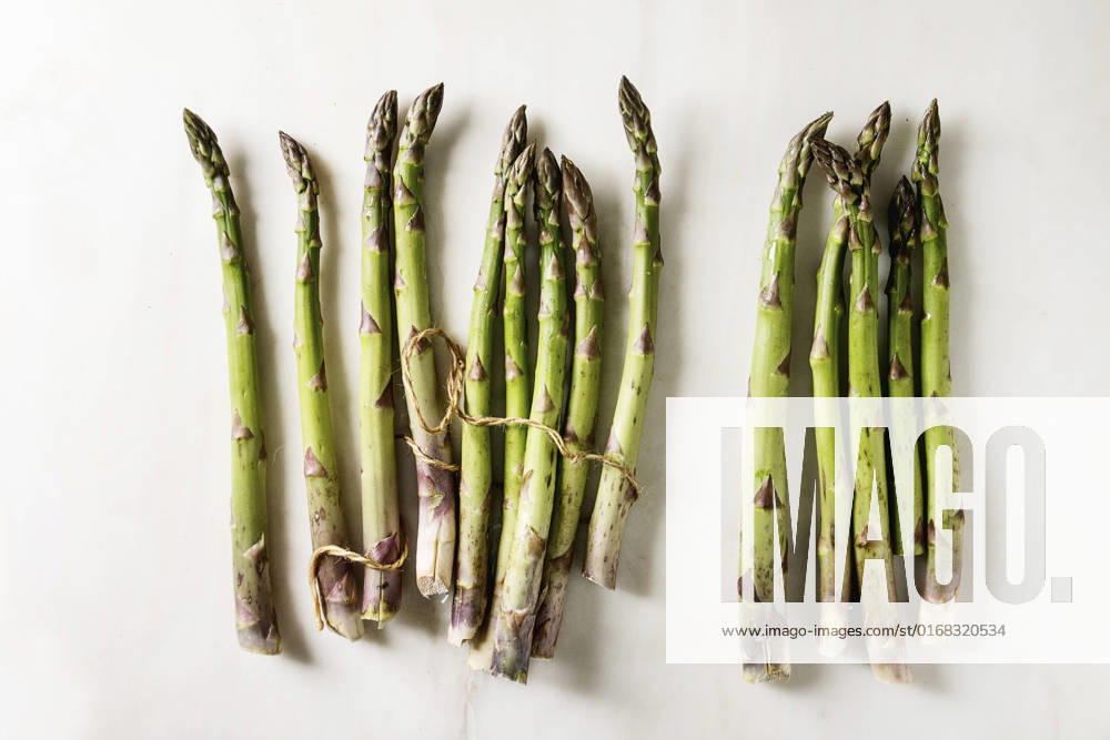 Bundle of green asparagus Bundle of raw organic green asparagus with thread over white marble background. Flat lay, space
