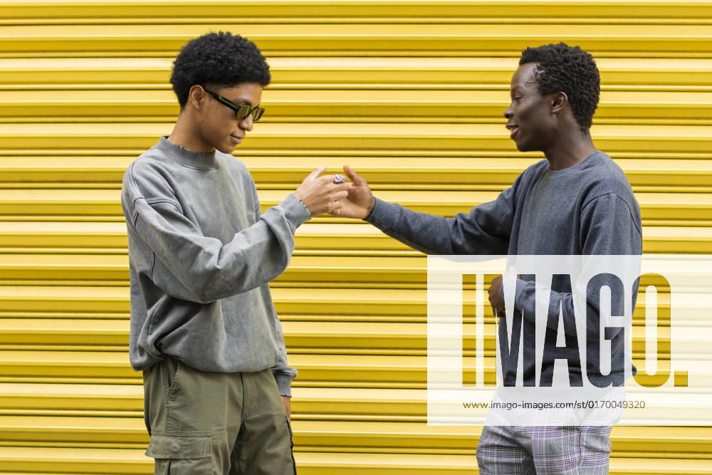 Friends greeting each other in front of yellow shutter model released, Symbolfoto, EGCF00035