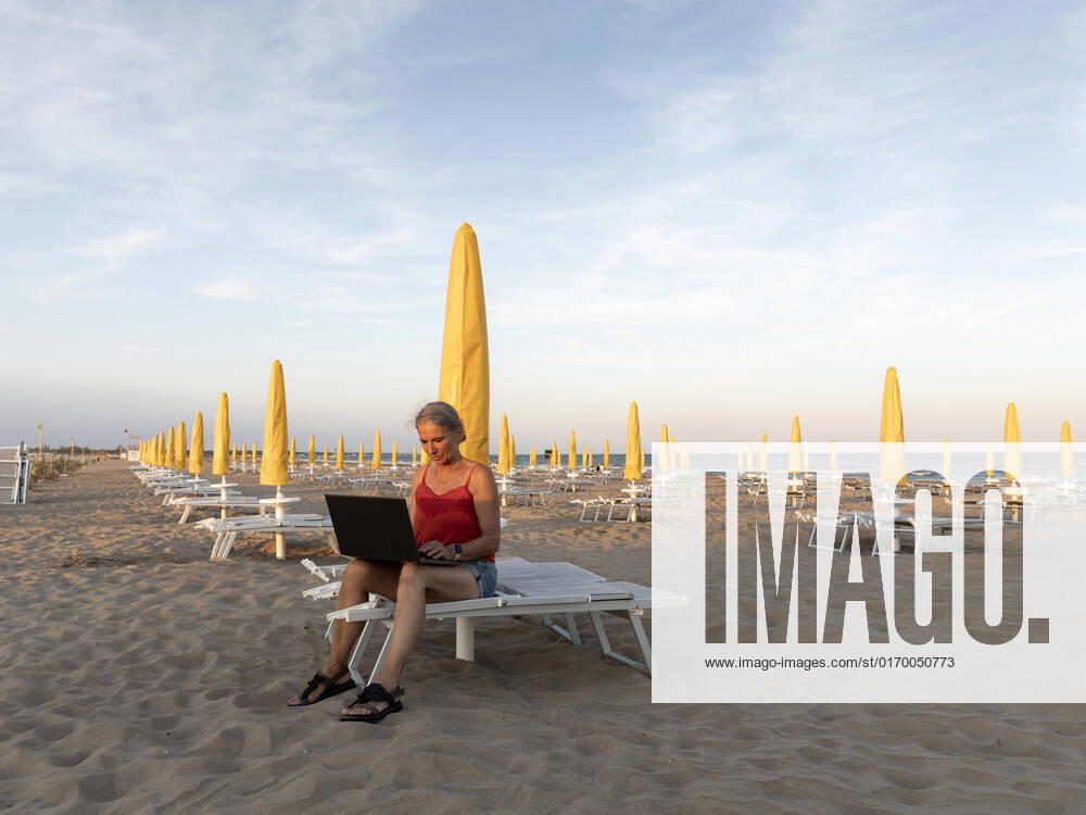 IMAGO Creative: Business - Work-Life Balance Senior businesswoman using laptop at beach model released, Symbolfoto, FLLF00673