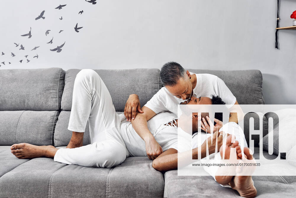 Affectionate gay couple kissing on sofa at home model released, Symbolfoto property released, GGGF01073