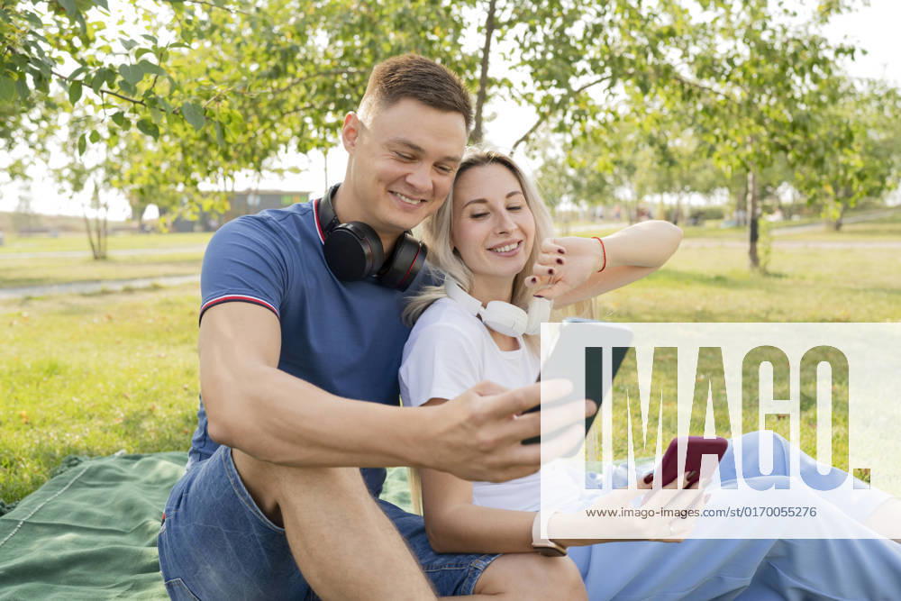 Young man and woman talking on video call through smart phone in park model released, Symbolfoto, LESF00163