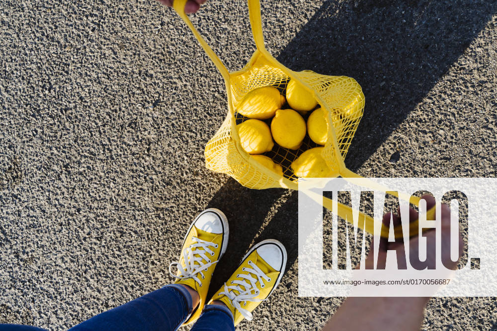 Woman standing on road opening mesh bag with lemons model released, Symbolfoto, OSF00812