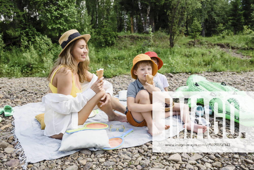 Woman eating ice cream with sons sitting on picnic blanket model released, Symbolfoto, VBUF00136
