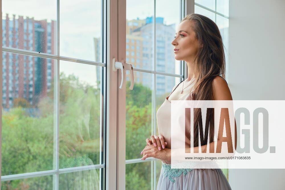 Nachdenkliche Woman looks through the Window to House