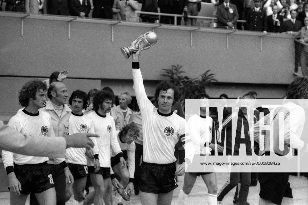 Schlußjubel Weltmeister BR Deutschland, v.li.: Rainer Bonhof, Bundestrainer Helmut Schön, Gerd Müller, Paul Breitner, Bernd Hölzenbein, Franz Beckenbauer mit dem WM Pokal, Wolfgang Overath, Masseur Erich Deuser, Torwart S. Maier Fußball WM Herren Weltmeisterschaft 1974, Nationalmannschaft, Nationalteam, Nationaltrikot, Länderspiel, Finale Totale Siegerehrung, Podium, Podest München Glück, Begeisterung, Freude,