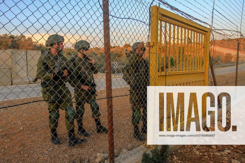 An Israeli soldier opens the gate of the separation barrier in the northern occupied West Bank for Palestinian farmers to enter their lands confiscated by Israel. Palestinian farmers closed the gates located on the wall separating the city of Salfit and the Jewish settlement of Ariel to reach their confiscated lands to pick olives, after the Israeli army opened them at seven in the morning and closed them until four in the evening and reopened them for the farmers to leave. Salfit Palestine - ZUMAs197 20221102_zaa_s197_140