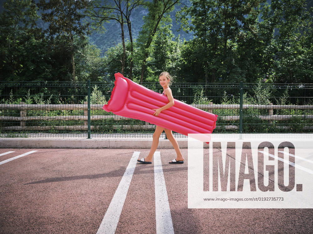 Smiling girl walking with pink inflatable pool raft on sunny day model released, Symbolfoto, DIKF00699