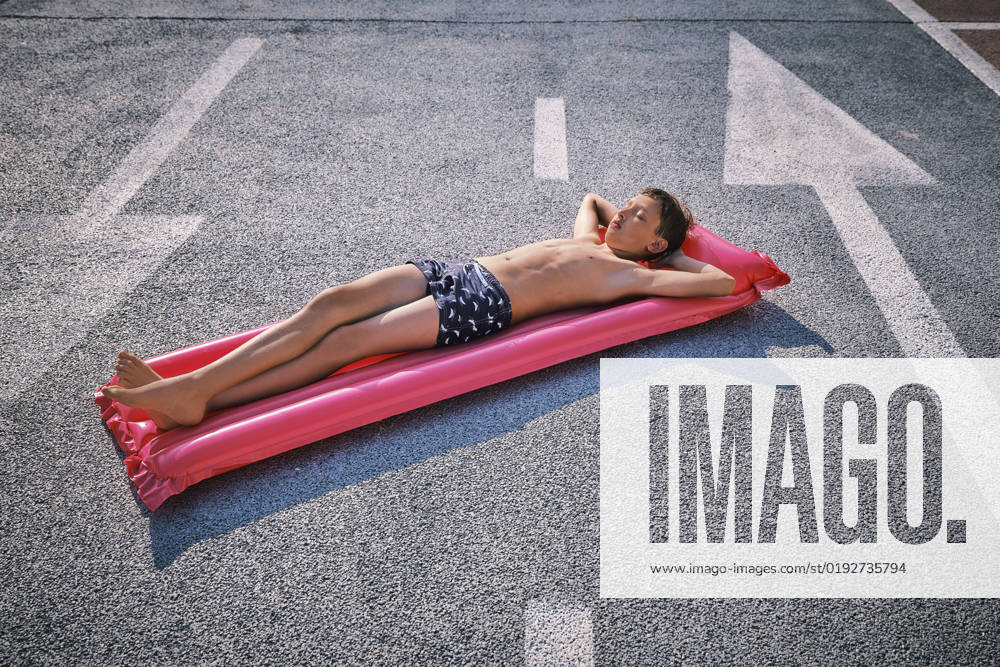 Shirtless boy lying on inflatable pool raft in parking lot model released, Symbolfoto, DIKF00703