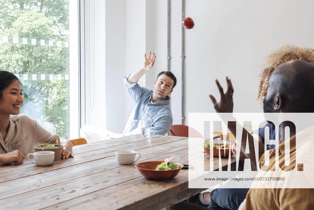 Businessman throwing apple at healthy lunch in staff room with colleagues model released, Symbolfoto property released, WESTF25075