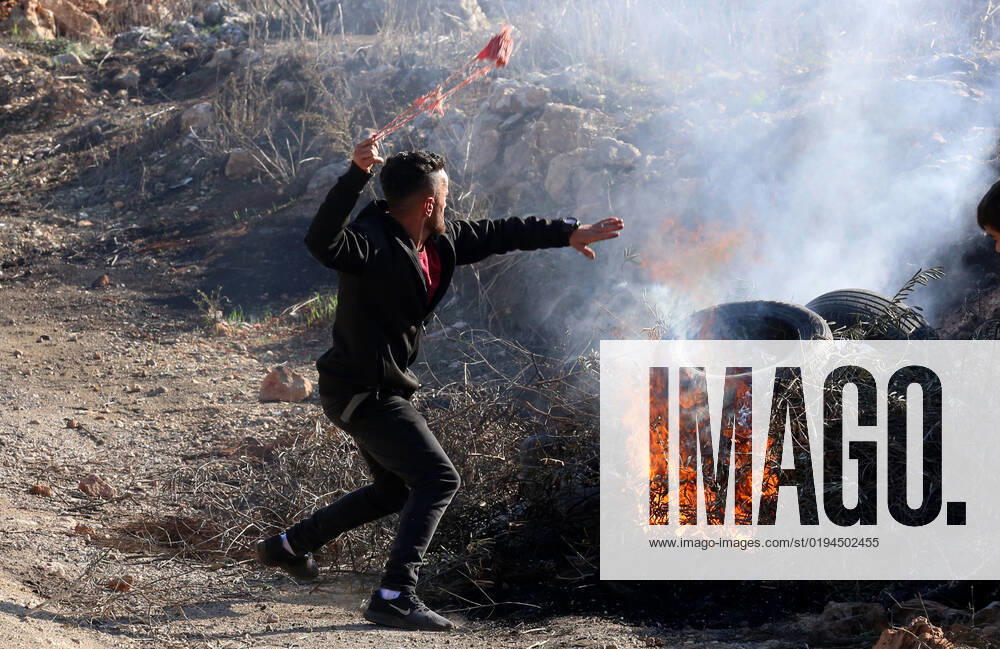 (221119) -- NABLUS, Nov. 19, 2022 -- A protester uses a slingshot to hurl a stone at Israeli soldiers following a protest against the expanding of Jewish settlements in the village of Beita, south of the West Bank city of Nablus, on Nov. 18, 2022. (Photo by Xinhua) MIDEAST-NABLUS-CLASHES NidalxEshtayeh