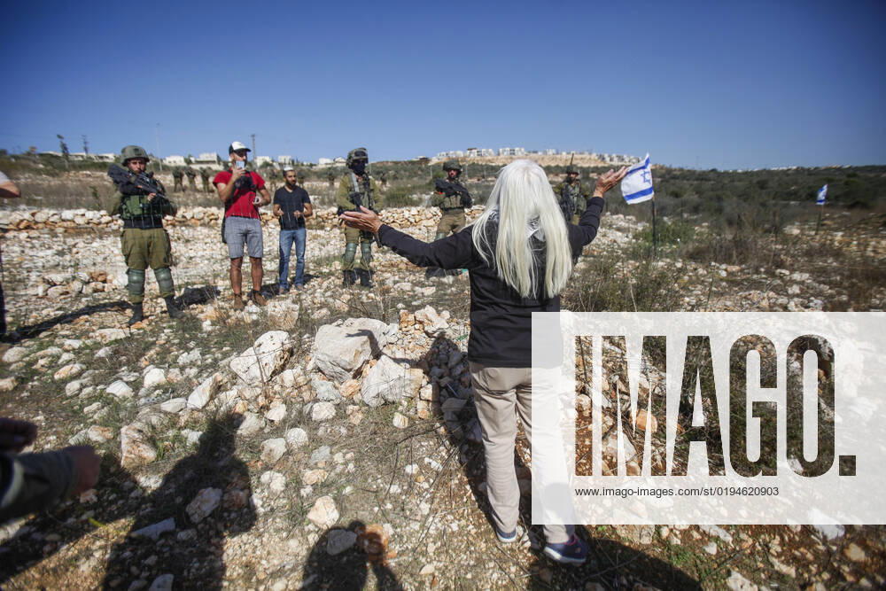Salfit, West bank, Palestine: A Palestinian protester demonstrates infront of Israel soldiers and Jewish settlers against the seizure of Palestinian farmers lands in the village of Burqin, west of Salfit, in the occupied West Bank. Palestinians demonstrated against the confiscation of their land by these settlers in favor of the Jewish settlement of Brochin. Salfit Palestine - ZUMAs197 20221120_zaa_s197_077