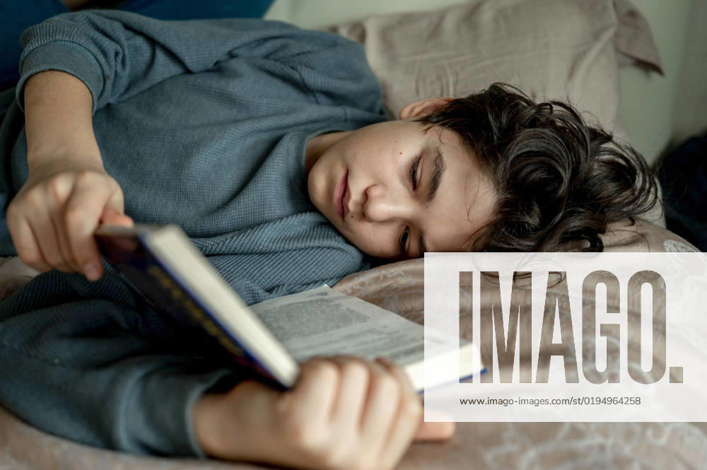 Boy reading novel lying on bed at home model released, Symbolfoto property released, ANAF00494
