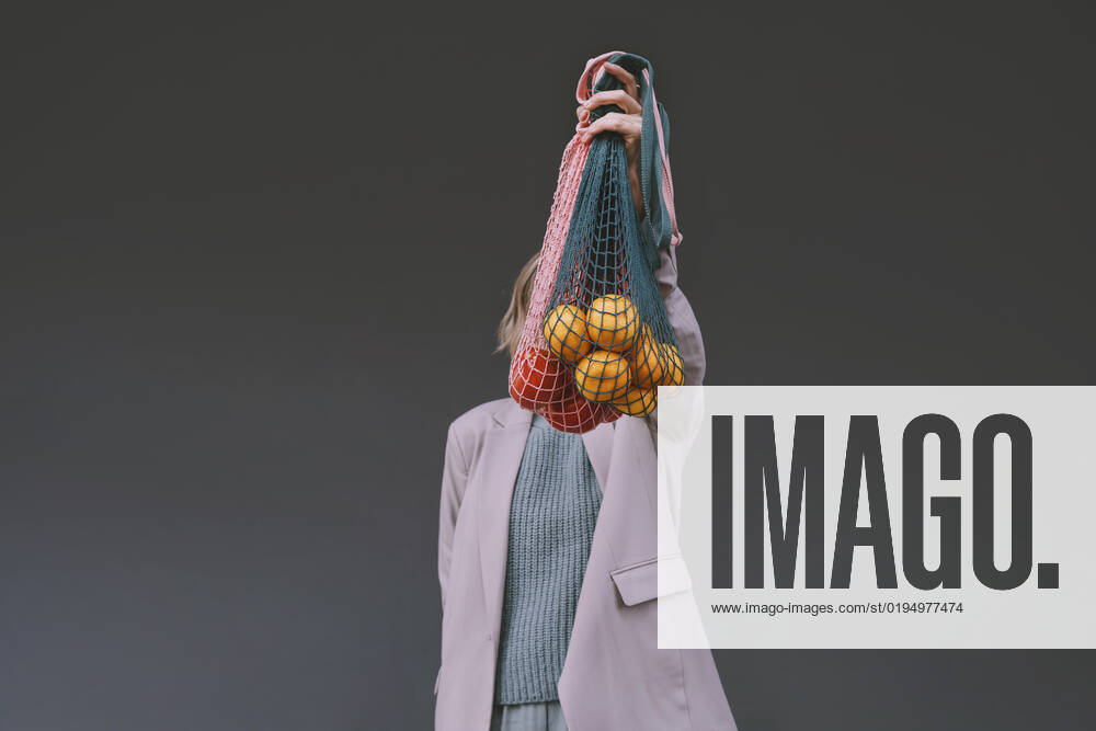 Woman covering face with mesh bag in front of gray wall model released, Symbolfoto, NDEF00065