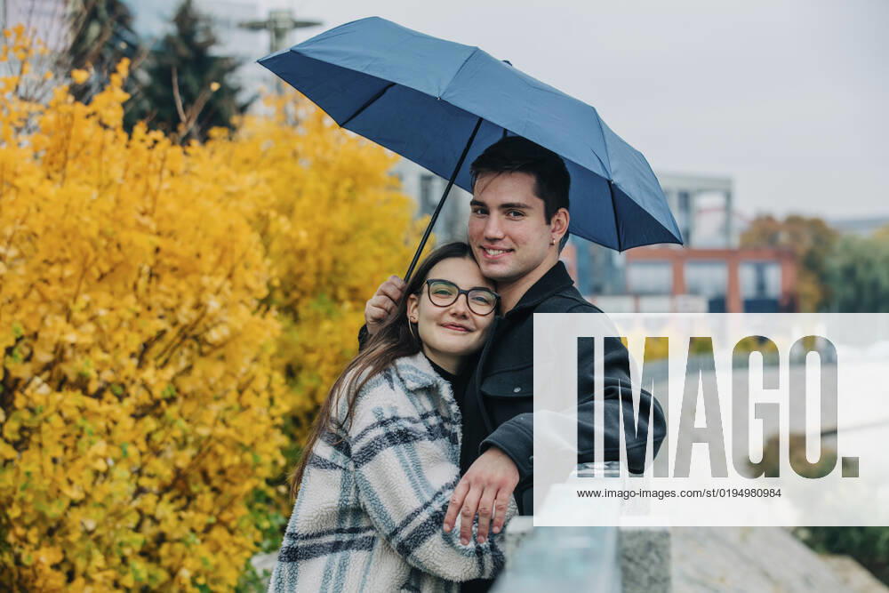 Smiling woman embracing boyfriend under umbrella in autumn model released, Symbolfoto, VSNF00107