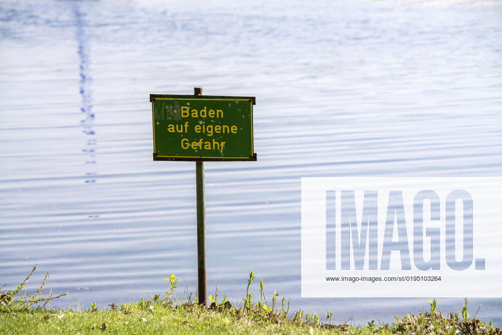 Warnschild am Badesee Warnschild mit der Aufschrift Baden auf eigene Gefahr an einem See.