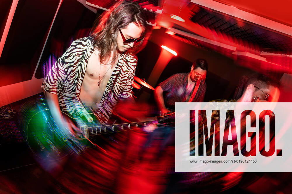 Young guitarist with long hair in sunglasses and striped shirt performing music on electric guitar during rehearsal with band, Model released, Property released ManuelRuiz_ID9449_285156_076