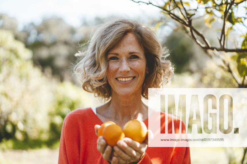 Happy blond woman with organic orange fruits model released, Symbolfoto property released, JOSEF15688