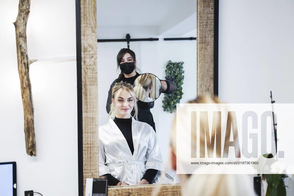 Hairdresser showing hairstyle to customer through mirror at salon model released, Symbolfoto property released, NJAF00066