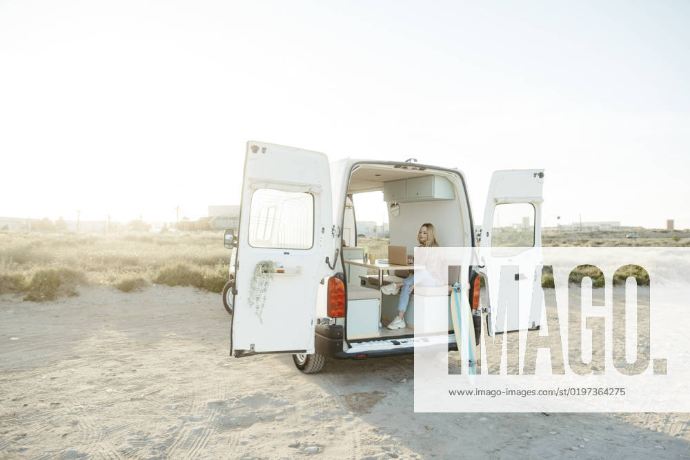 Young freelancer sitting with laptop in caravan in front of clear sky model released, Symbolfoto property released, RCPF01496