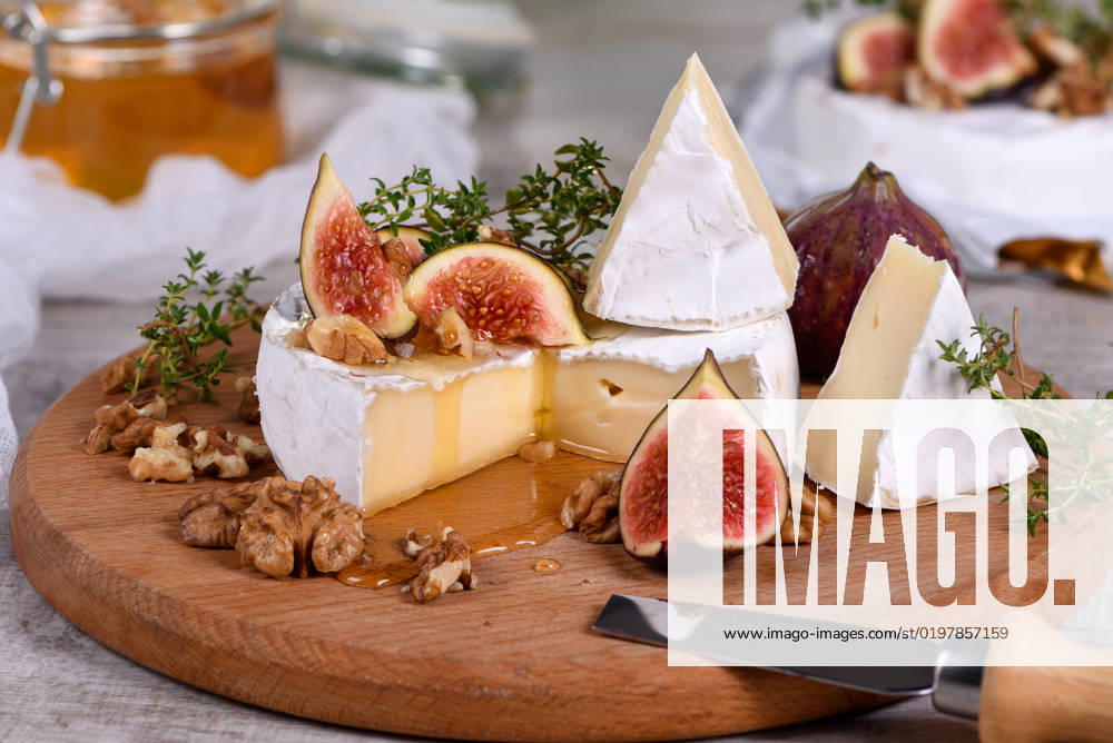Brie cheese with honey and figs Brie cheese served on a wooden board with figs, walnuts and honey