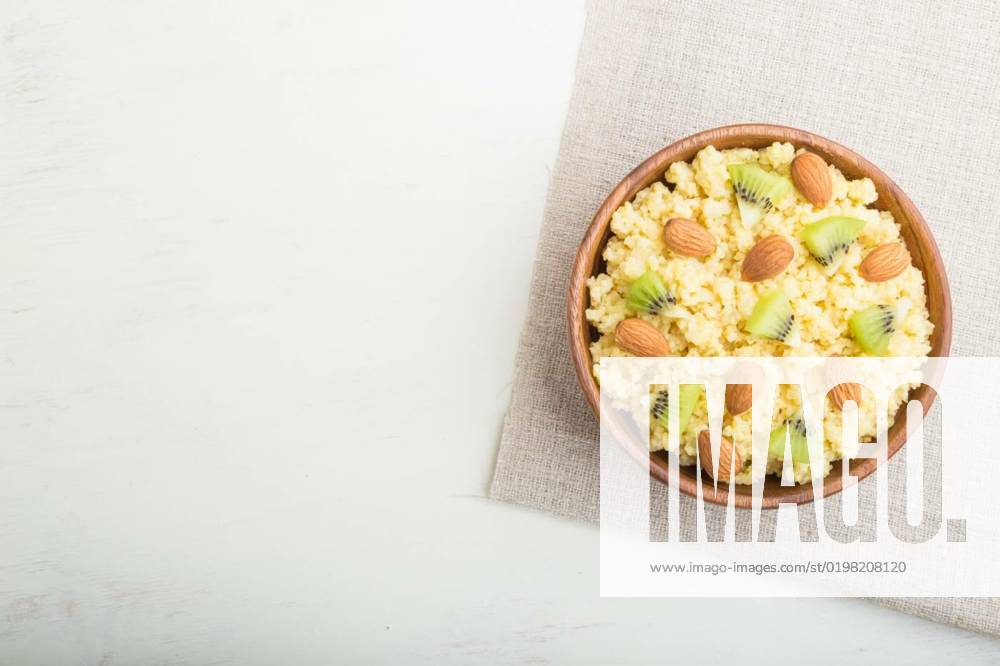 Millet porridge with kiwi and almonds in wooden bowl on a white wooden background. Top view, copy space., Millet porridge with kiwi and almonds in wooden bowl on a white wooden background and linen textile. Top view, flat lay, copy space., Millet porridge with kiwi and almonds in wooden bowl on a white wooden background and linen textile. Top view, flat lay, copy space., 21.10.2022,