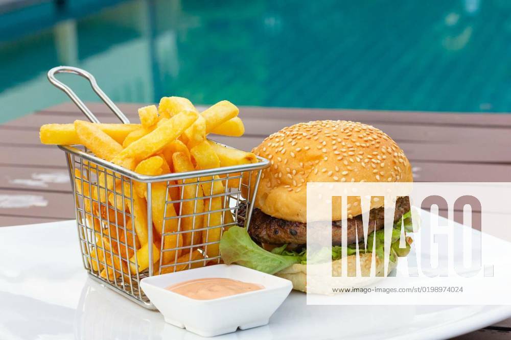 Classic burger with stainless steel basket of french fries and pink sauce dip, Classic burger with stainless steel basket of french fries and pink sauce dip plate by swimming pool. Chicken hamburger at fancy restaurant, fast food combo meal concepts, Classic burger with stainless steel basket of french fries and pink sauce dip plate by swimming pool. Chicken hamburger at fancy restaurant, fast food combo meal concepts, 01.12.2022,
