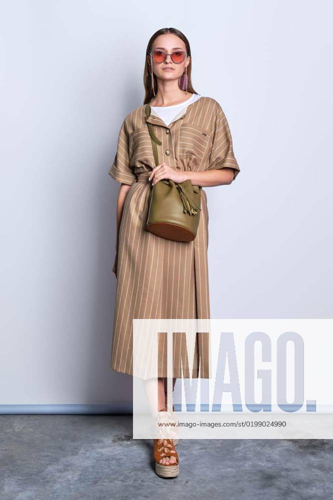 Trendy lady in big sunglasses wearing striped dress with handbag posing, Trendy lady in big sunglasses wearing striped olive dress with leather handbag posing over gray background, Trendy lady in big sunglasses wearing striped olive dress with leather handbag posing over gray background model released, Symbolfoto , 08.12.2022,