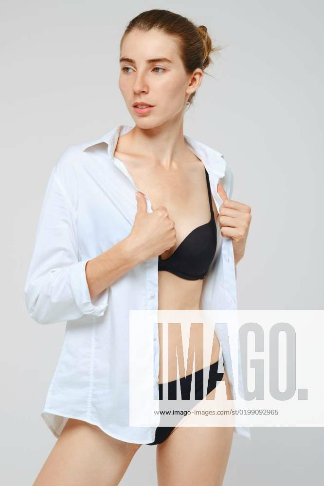 Woman in black underwear takes off white shirt, Young woman in black underwear takes off white shirt, Young woman in black underwear takes off white shirt model released, Symbolfoto , 17.12.2022,
