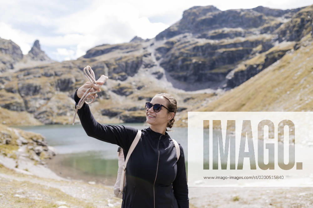 Smiling hiker taking selfie through mobile phone model released, Symbolfoto, MEF00148