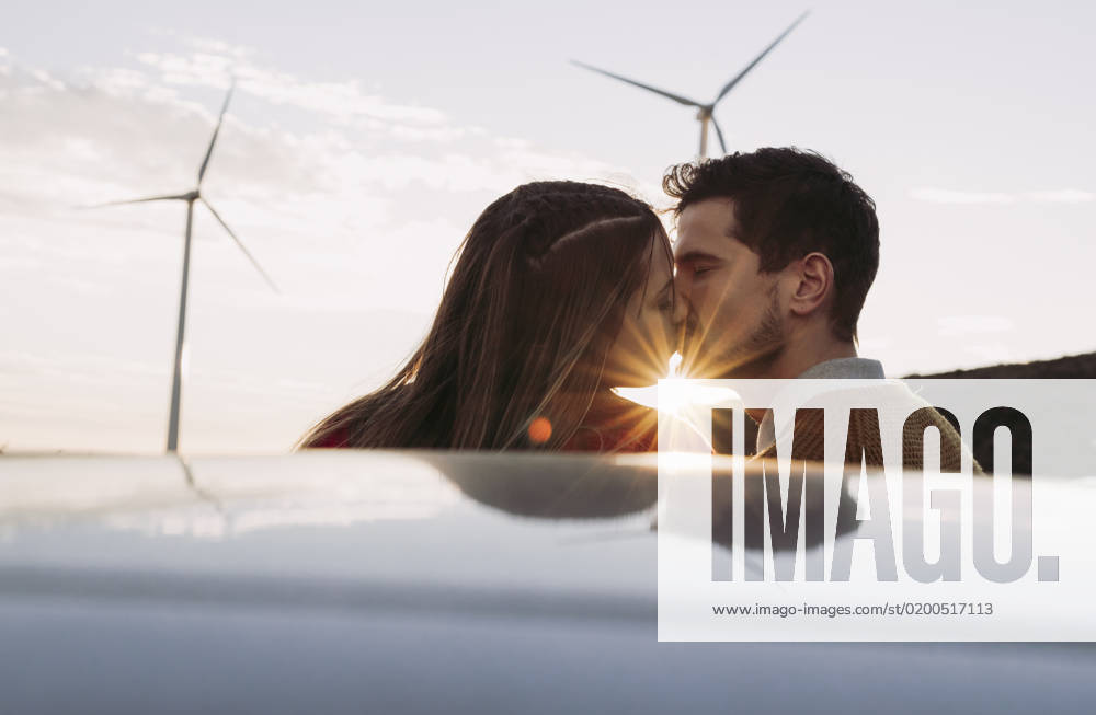 Couple kissing by car at sunset with wind farm in background model released, Symbolfoto, LJF02377