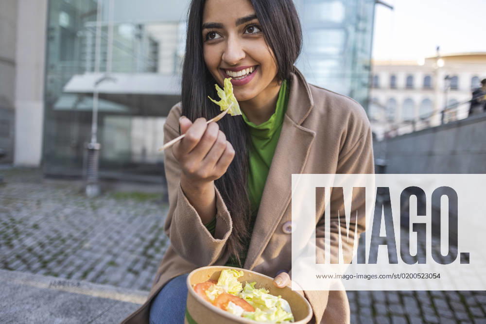 Happy young woman eating lunch sitting outside building model released, Symbolfoto, JCCMF08943