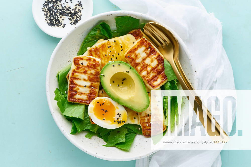 Keto ketogenic diet soft boiled eggs with avocado and lettuce on pastel background closeup top view keto ketogenic diet soft boiled eggs with grilled haloumi, avocado and lettuce, mediterranean cuisine on pastel background