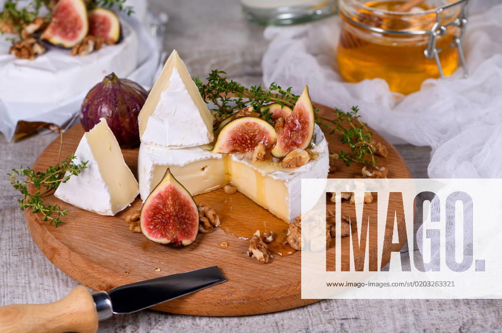 Brie cheese with honey and figs Brie cheese served on a wooden board with figs, walnuts and honey